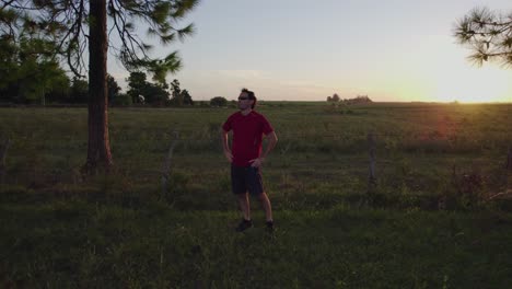 Joven-Haciendo-Ejercicios-De-Estiramiento-Para-Relajarse-Mientras-Levanta-Los-Brazos-En-La-Naturaleza-Al-Atardecer