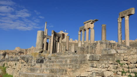 Ancient-Roman-ruins-in-Dougga-with-blue-skies,-showcasing-history-and-architecture