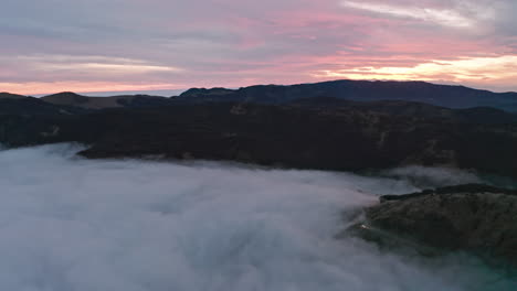 Montañas-Brumosas-Al-Amanecer-Con-Cielos-Rosados-Suaves,-Vista-Aérea