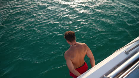 Young-athletic-male-diving-from-Mallorca-sailing-yacht-into-crystal-clear-turquoise-ocean-with-splash