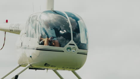 Close-up-of-Robinson-R44-Helicopter-taking-off-from-a-field-and-flying-towards-the-camera