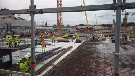 Stahlstangen-Im-Vordergrund-Von-Männern,-Die-Auf-Einer-Großen-Baustelle-In-Stockholm-Arbeiten