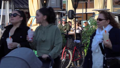 Close-view-of-people-walking-past-customers-sitting-at-outdoor-bar-in-Stockholm