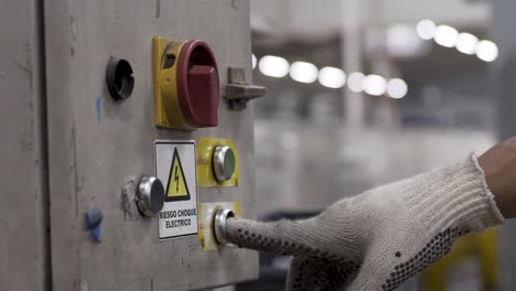 Worker-operates-industrial-button-with-safety-glove-in-a-factory,-close-up