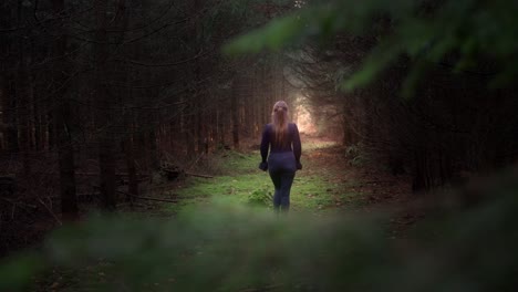 Young-girl-with-long-hair-walks-out-into-the-glow-between-the-trees