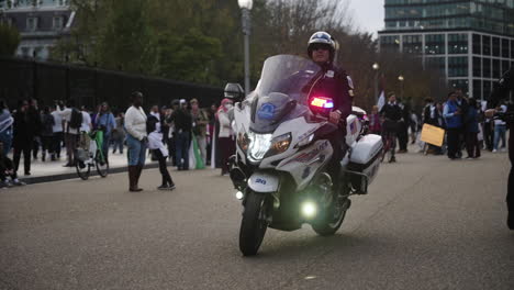 Eine-Zeitlupenaufnahme-Eines-Polizisten-Auf-Einem-Motorrad,-Der-Während-Einer-Protestaktion-Vorbeifährt
