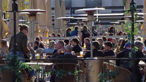 Menschen-Sitzen-Im-Freien-In-Einem-Restaurant-In-Stockholm,-Während-Im-Vordergrund-Menschen-Vorbeigehen