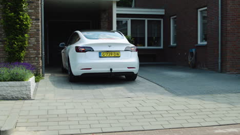 White-Tesla-drives-up-on-driveway,-arriving-home-concept,-after-grocery-shopping