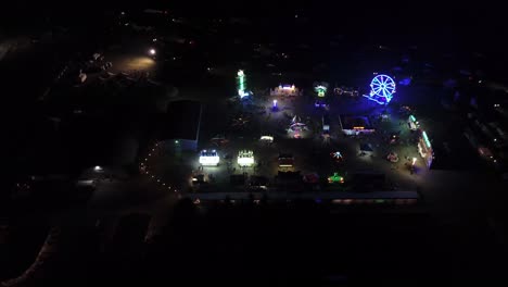 Bulkley-Valley-Fairground-at-Night-with-Neon-Flashing-Colorful-Lights-from-an-Aerial-Drone-Panning-Overhead