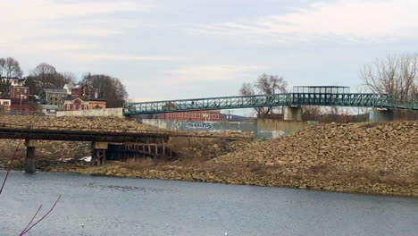 Wide-angle-view-of-people-crossing-a-river-on-a-metal-bridge-in-an-industrial-town