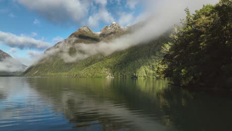 Lake-Gunn-in-New-Zealand-with-clouds-against-mountain-slope-on-sunny-day