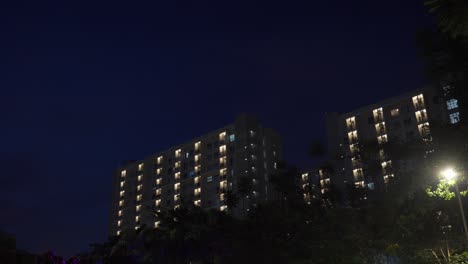 Mehrfamilienhaus-In-Der-Nacht-Mit-Lichtern,-Die-Einen-Einblick-In-Das-Stadtleben-Bieten