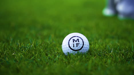 Golf-ball-getting-hit-by-a-golf-club-in-slow-motion,-beautiful-short-green-grass