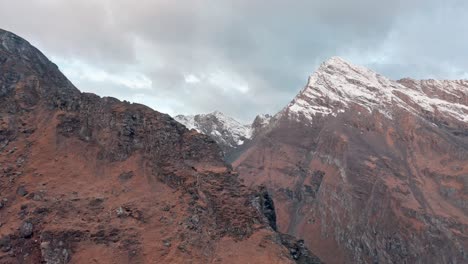 Schneebedeckter-Berggipfel-Mit-Zerklüftetem-Gelände-Und-Rötlichen-Felsen-In-Der-Dämmerung