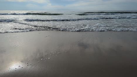 Leichte-Brandung-Am-Sandstrand-Bei-Sonnenuntergang-Mit-Leichten-Wolken-In-Zeitlupe