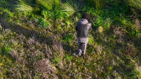 Oben-Ansicht-Eines-Fotografen,-Der-Sein-Stativ-Und-Seine-Kamera-In-Einer-Grasbewachsenen-Naturlandschaft-Hält