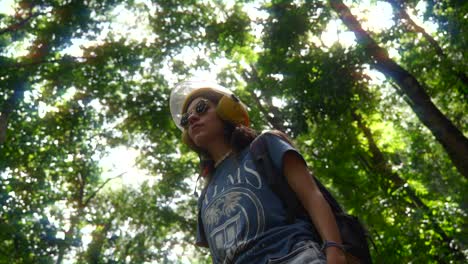 Woman-in-orange-motorbike-helmet-admires-mystical-forest-in-tropical-jungle
