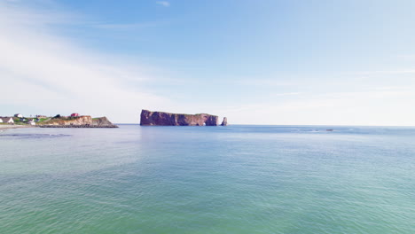 Drone-view-advancing-towards-Percé-Rock-above-the-Saint-Lawrence-River-during-a-sunny-day