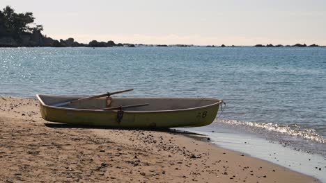 Lone-small-fishing-boat-parked-on-sandy-beach-against-backdrop-of-ocean