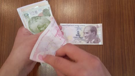 Ein-Teenager-Sortiert-Jede-Banknote-Der-Türkischen-Lira-Nach-Wert,-Mit-Einem-Porträt-Von-Atatürk,-Dem-Gründer-Der-Republik-Türkei,-Oben-Drauf