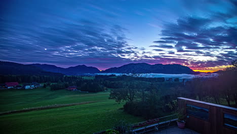 Zeitraffer-Sonnenaufgang-Mit-Lebendigen-Farben-über-Einer-Grünen-Landschaft,-Die-Von-Tiefem-Nebel-Bedeckt-Ist