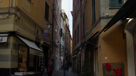 Narrow-street-or-alley-between-colorful-buildings-with-shops-and-apartments,-Varazze,-Italy