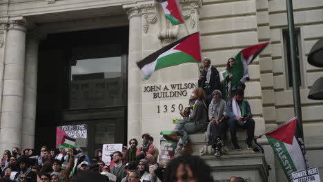 Un-Grupo-De-Manifestantes-Pro-Palestinos-Ondean-Banderas-En-Lo-Alto-De-Un-Edificio-Durante-Una-Gran-Protesta.