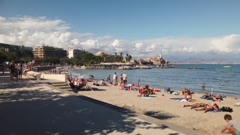 Children-play-and-people-lie-on-beach-in-summer-in-Antibes,-France