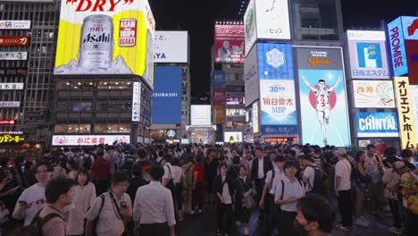 Nächtliche-Bewegtbildaufnahme-Durch-Die-Menschenmassen-Und-Beleuchteten-Schilder-An-Der-Ebisubashi-Brücke-Auf-Dem-Dotonbori-Kanal-In-Osaka,-Japan