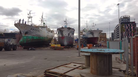 People-work-on-freighter-ships-at-a-boatyard-near-the-harbor-in-central-Cape-Town,-South-Africa