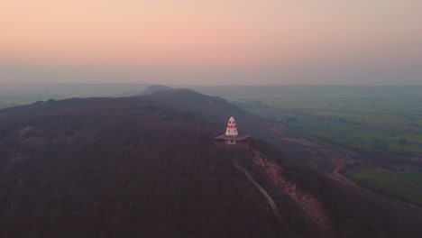 Aerial-Drone-shot-of-a-Hindu-Temple-on-Hill-top-with-stairs-leading-to-it-during-sunset-time-in-a-village-of-Gwalior-in-Madhya-Pradesh-India