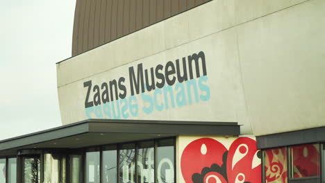 Outside-Zaans-Museum,-with-people-walking-past-frame,-narrow-shot-of-letters,-focus-on-background