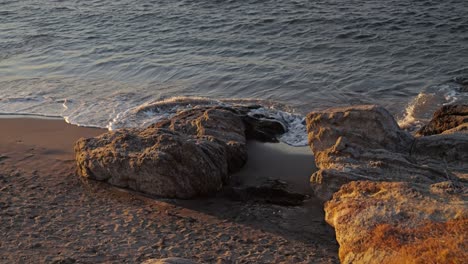 Pequeñas-Rocas-Con-Olas-Que-Llegan-Durante-La-Puesta-De-Sol-En-El-Océano.