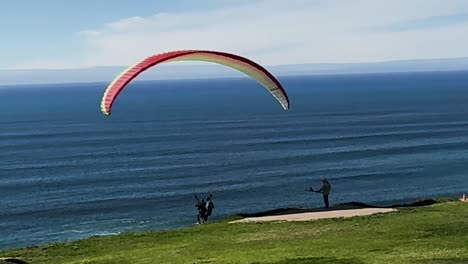 Para-gliders,-jumping-off-the-cliff-and-taking-off-along-the-coast-in-fast-motion-on-a-beautiful-sunny-day-at-Torrey-Pines-Gliderport-in-La-Jolla,-California