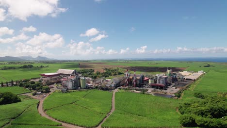 Eine-Zuckerfabrik-In-Mauritius-Inmitten-Grüner-Felder-Unter-Blauem-Himmel,-Industrie-Trifft-Landwirtschaft,-Luftaufnahme