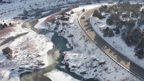 Early-morning-snowy-winter-river-scene-from-above-along-side-a-road-or-highway