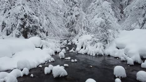 Río-De-Invierno-Bajo-Y-Cercano-Sobrevolado-Con-Montículos-De-Nieve