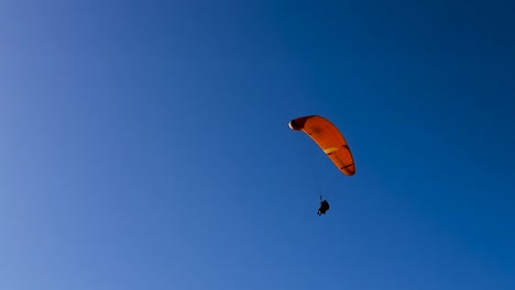 Gleitschirm-Mit-Wunderschönem-Orangefarbenem-Segelflugzeug-Fliegt-über-Den-Strahlend-Blauen-Himmel-Am-Torrey-Pines-Gliderport-In-La-Jolla,-Kalifornien