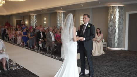 La-Novia-Y-El-Novio-Intercambian-Votos-Durante-La-Ceremonia-De-Boda,-Los-Invitados-Miran