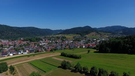 View-over-Zell-am-Harmersbach-in-the-Black-Forest,-fields-in-the-foreground,-mountains-in-the-background