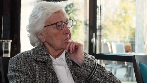 Aged-woman-with-white-hair-and-glasses-looking-and-shaking-no-with-her-head