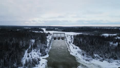 Paisaje-De-Clip-Largo-Establecimiento-De-Un-Disparo-Aéreo-De-Drones-Agua-Corriendo-Enorme-Notigi-Energía-Hidroeléctrica-Presa-Del-Lago-En-El-Invierno-Nevado-Del-Norte-De-Manitoba-Canadá