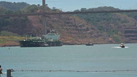 Static-shot-of-a-ship-being-taxied-through-Panama-Canal-with-Centenario-Bridge