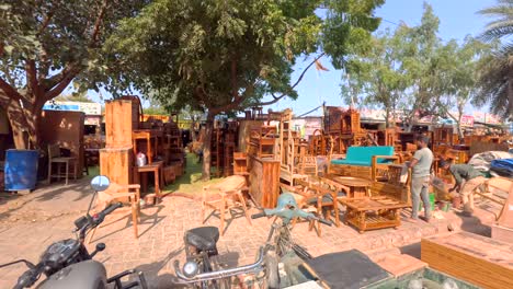 Young-Indian-men-cleaning-wood-while-woodworking-display-of-completed-furniture-is-displayed-on-the-roadside-in-Sikanderpur-market