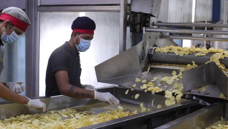 POV-Aufnahme-Von-Männern,-Die-Schlechte-Chips-Herausziehen-Und-Chips,-Die-In-Den-Verpackungsprozess-Gehen