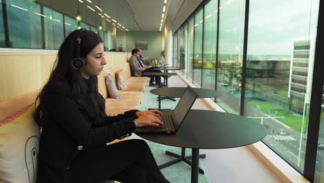 Cute-woman-working-behind-her-laptop-in-office-restaurant,-amazing-view-outside