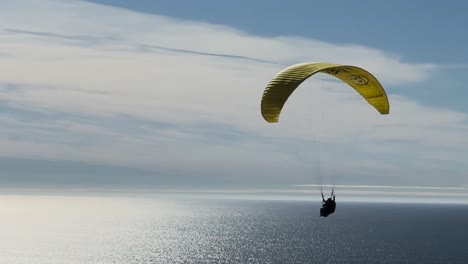 Tandem-paragliders-fly-across-coast-with-La-Jolla-Cove-in-the-background-at-Torrey-Pines-Gliderport-in-La-Jolla,-California