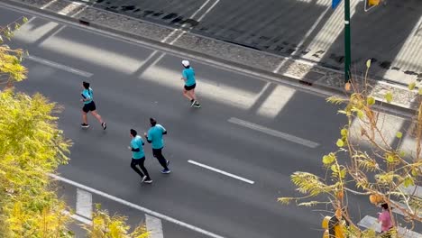 Vista-Aérea-De-Corredores-De-Maratón-Tomando-El-Control-De-Una-Calle-De-La-Ciudad.