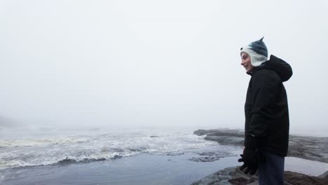 Young-boy-standing-on-the-rocks-on-a-coastal-landscape