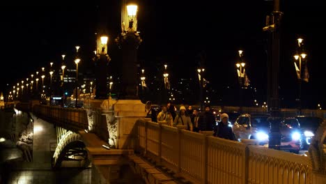 Blick-Auf-Die-Innenstadt-Von-Budapest-Mit-Margaretenbrücke-Und-Donau-Bei-Nacht,-Lichtreflexionen,-Verkehr-Und-Menschen-In-Bewegung,-Mittlere-Aufnahme